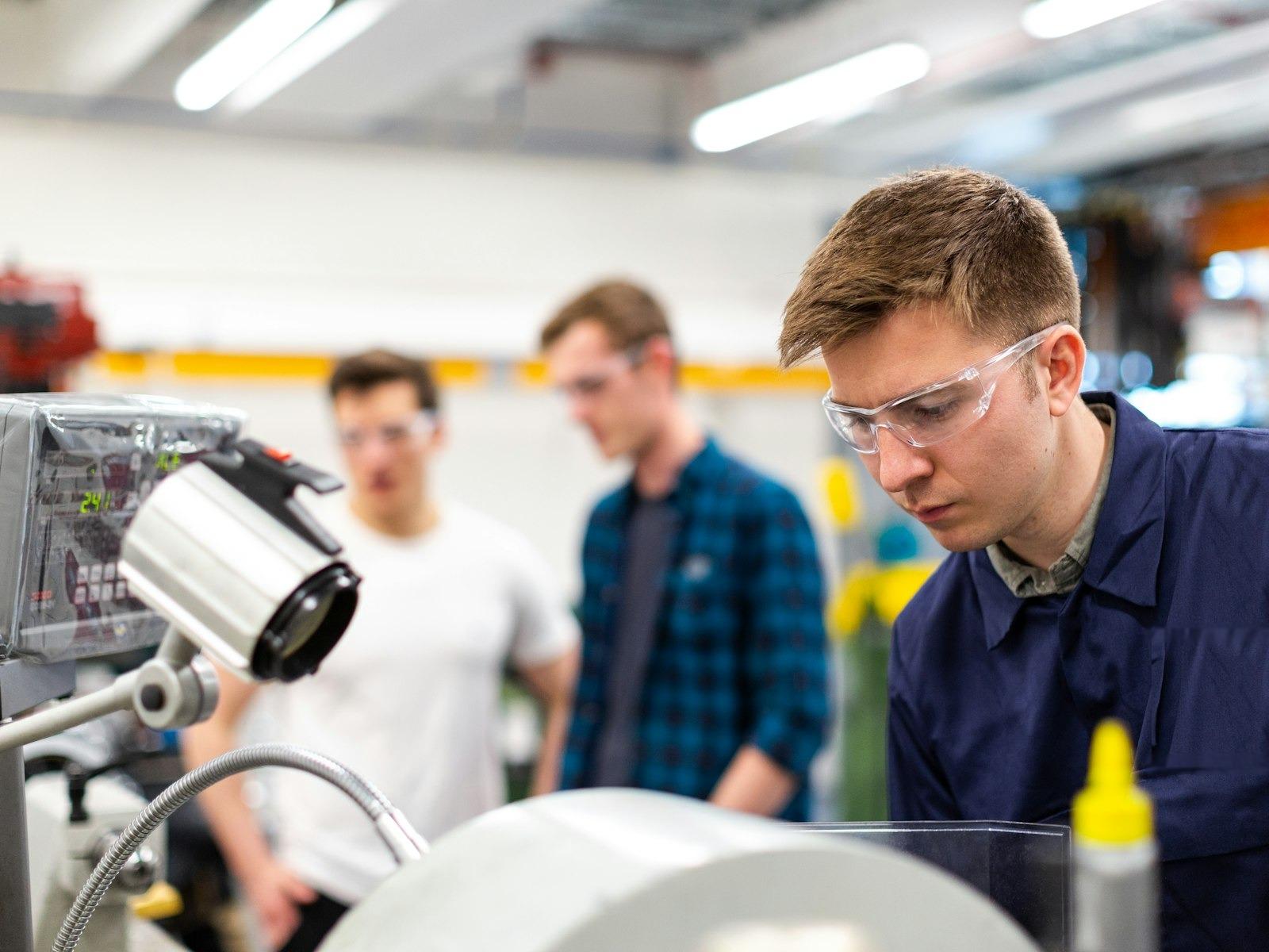 Engineers examining machinery and instrumentation in a manufacturing lab — real operational complexity